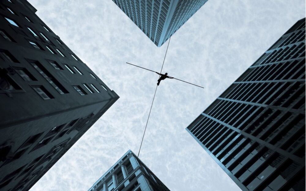 Tightrope walker balancing between two skyscrapers, symbolizing business risk and challenges